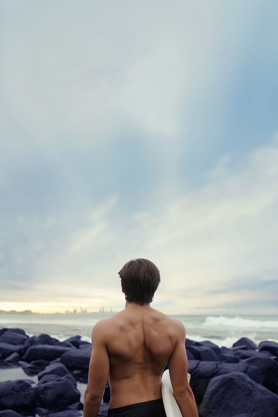 persona, de peu, portar, taula de surf, vora del mar, home, rocós, vora de la platja, celebració, blanc, home de negre, fons negre, pedra, durant el dia, oceà, esquena, surfista, rock, homes, sense camisa, a l'aire lliure, una persona, adult, mascles, vista del darrere, ètnia caucàsica, cel, platja, construcció muscular, mar, naturalesa, dia, un sol home, estiu, núvol - cel, aigua, persones reals, estils de vida, bellesa a la natura, escenics - natura, activitat d'oci, rock - object, festa, terra, horitzó sobre l’aigua, mirant la vista, 5K