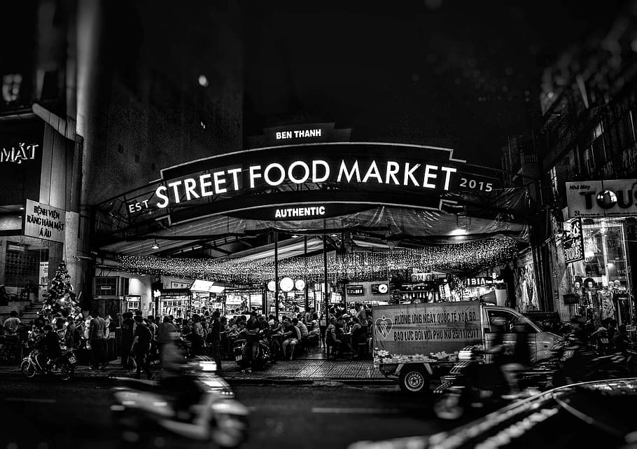 gråtoneskud, street food markedet, gademad markedsfacade, tekst, meddelelse, vestlige script, transportmidler, by, gade, arkitektur, transportform, bygget struktur, skilt, nat, bil, land køretøj, motor køretøj, bygning udvendig, belyst, gruppe af mennesker, tilfældige mennesker, byliv, manuskript, 5K