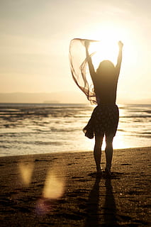 woman, holding, scarf, standing, beach shore, sunset, beach, shore, sea, silhouette, back Lit, outdoors, women, summer, people, sunlight, one Person, water, nature, happiness, fun, females, lifestyles, freedom, sun, vacations, sky, healthy Lifestyle, enjoyment, cheerful, dusk, young Adult, carefree, joy, horizon over water, land, horizon, beauty in nature, full length, leisure activity, real people, rear view, arms raised, human arm, 4K, CC0, public domain, royalty free