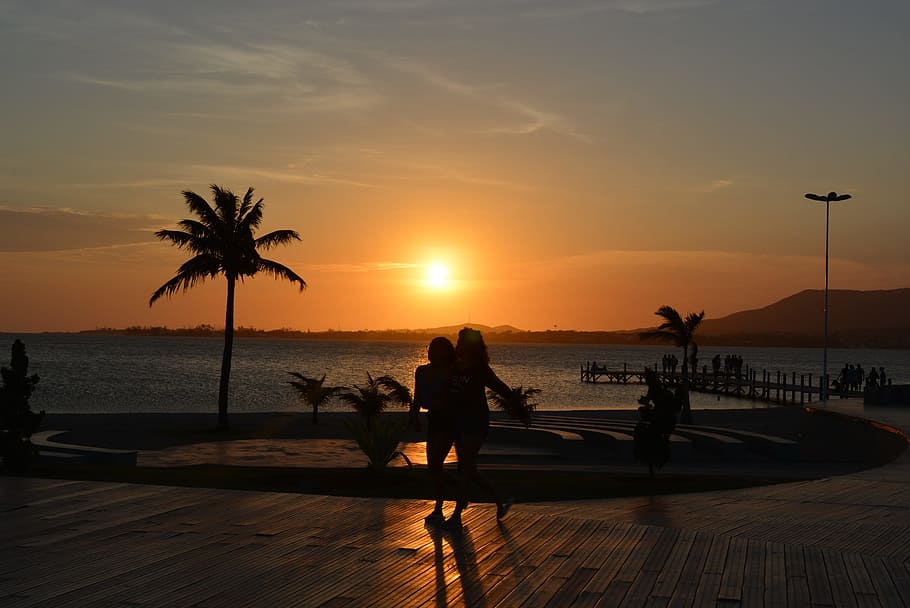 Sonnenuntergang, Sol, Strand, Dämmerung, Gewässer, Sommer-, Ozean, Himmel, Wasser, echte Menschen, Meer, Schönheit in der Natur, Baum, Palme, Szenen - Natur, Silhouette, orange Farbe, Natur, Freizeitbeschäftigung, Lebensstile, Sonnenlicht, Frau, Gruppe von Leuten, tropisches Klima, Sonne, Horizont über Wasser, draußen, 2K