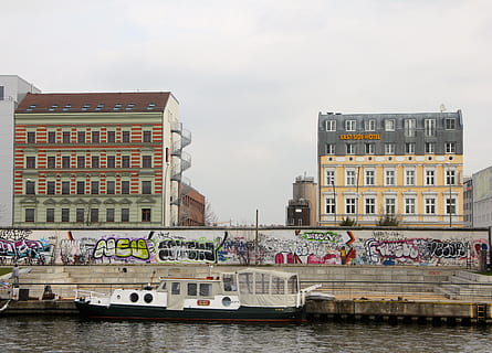 Berlin, Ostseite, Deutschland, Strukturen, Graffiti, Gebäudehülle, die Architektur, gebaute Struktur, Wasser, Ufergegend, Wasserfahrzeug, Stadt, Transportmittel, Transport, Himmel, Gebäude, Fluss, Natur, Tag, Reise, Reiseziele, Gruppe von Leuten, große gruppe von menschen, draußen, Passagierfahrzeuge, 2K, CC0, gemeinfrei, lizenzfrei