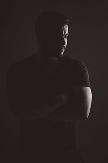 man, black, t-shirt, standing, wall, low light photography, studio, portrait, light, boy, lights, in relation to, about, men, one Person, adult, people, caucasian Ethnicity, studio Shot, males, young Adult, male Beauty, black Background, black And White, dark, one man only, only men, indoors, front view, waist up, young men, lifestyles, cut out, three quarter length, serious, arms crossed, casual clothing, looking, contemplation, 4K, CC0, public domain, royalty free