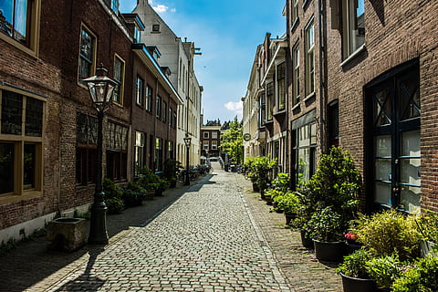 houses, clouds, street, buildings, architecture, bricks, daylight, exterior, outdoors, pavement, windows, building exterior, built structure, building, direction, residential district, the way forward, cobblestone, day, footpath, nature, city, plant, diminishing perspective, window, no people, sky, narrow, alley, long, row house, 5K, CC0, public domain, royalty free