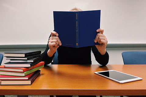 person, innehav, blå, bok, Sammanträde, framför, brun, trä-, tabell, läsa, lära sig, skola, studerande, utbildning, kunskap, studie, trådlös teknik, bara en man, en person, bärbar dator, vuxen, inomhus, skrivbord, endast vuxna, mänsklig kroppsdel, offentliggörande, läsning, aktivitet, inlärning, män, stack, papper, hanar, möbel, humör, litteratur, studerar, dolda ansikte, inbunden bok, 2K, CC0, offentligt domän, royaltyfria