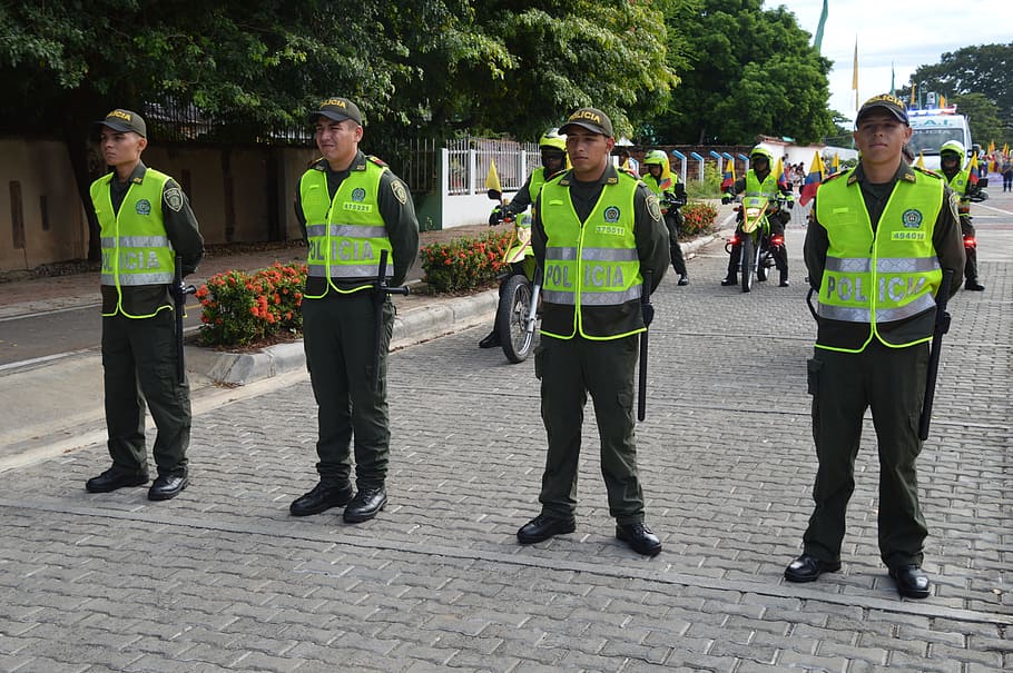 policija, aizsargi, cilvēku grupa, reāliem cilvēkiem, apģērbs, pilns garums, atstarojošs apģērbs, dienā, stāv, vīriešiem, drošību, augu, pilsēta, pieaugušais, portrets, cilvēkiem, skats no priekšas, skatoties uz kameru, iela, aizsardzību, zaļā krāsa, vienota, atbildību, valdība, 5K