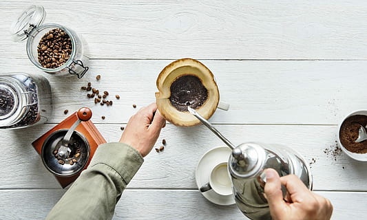 person, bedrift, tepotte, hælde, krus, kaffe, filter, bønner, kværn, hånd, holde, oppefra og ned, træ, bord, træbord, start op, stege, retro, slap af, forfriskende, professionel, forberede, forberedelse, en person, mad og drikke, menneskelig hånd, køkkenredskaber, mad, indendørs, menneskelig kropsdel, husholdningsudstyr, voksen, træ - materiale, direkte over, herrer, drikke, ske, spise redskaber, høj vinkel visning, 2K, CC0, offentligt domæne, royaltyfrie