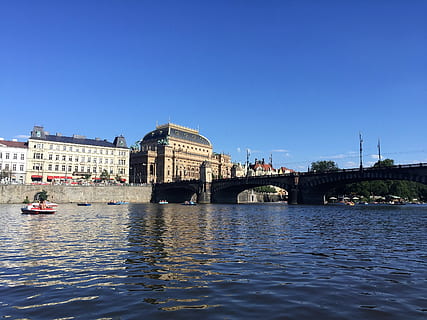 pragues, řeka, uklidnit, voda, stavba, architektura, exteriér budovy, most, spojení, přeprava, most - mužská konstrukce, město, nebe, modrý, nábřeží, čisté nebe, destinace, Příroda, způsob dopravy, námořní plavidlo, nikdo, venku, obloukový most, osobní plavidlo, 2K, CC0, veřejná doména, bez autorských práv