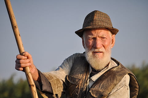 man, wearing, hat, holding, wooden, rod, gray, sky, activity, beard, elderly, fedora, fisherman, male, old, person, portrait, royalty  images, one person, adult, headshot, men, facial hair, senior adult, occupation, males, looking at camera, clothing, front view, nature, senior men, emotion, day, mustache, farmer, human face, contemplation, 2K, CC0, public domain, royalty free