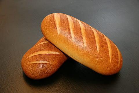 two oval breads, napoli bread, bread, food, dining, speciality, craft, baker, taste, freshly baked, oven, production, bakes bread, loaf of Bread, brown, freshness, bakery, breakfast, baguette, bun, organic, seed, food and drink, healthy eating, wellbeing, indoors, orange color, close-up, no people, table, fruit, studio shot, simplicity, still life, wood - material, slice, rustic, french food, orange, 2K, CC0, public domain, royalty free