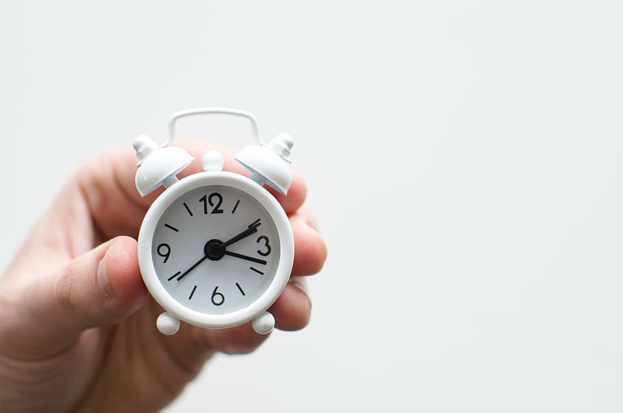 person, holding, white, analog desk clock, tiny, alarm, clock, time, hand, alarm Clock, human Hand, morning, copy space, clock face, human body part, single object, minute hand, number, studio shot, deadline, indoors, white background, close-up, second hand, cut out, checking the time, finger, chrome, countdown, 5K