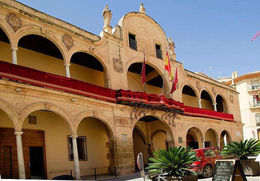 espanya, lorca, Ajuntament, banderes, arquitectura, arcades, arc, exterior de l'edifici, a l'aire lliure, estructura construïda, destinacions de viatge, cel, història, el passat, naturalesa, cel clar, edifici, cap gent, viatjar, vista d’angle baix, turisme, dia, columna arquitectònica, vermell, ciutat, pati, arquejat, 2K