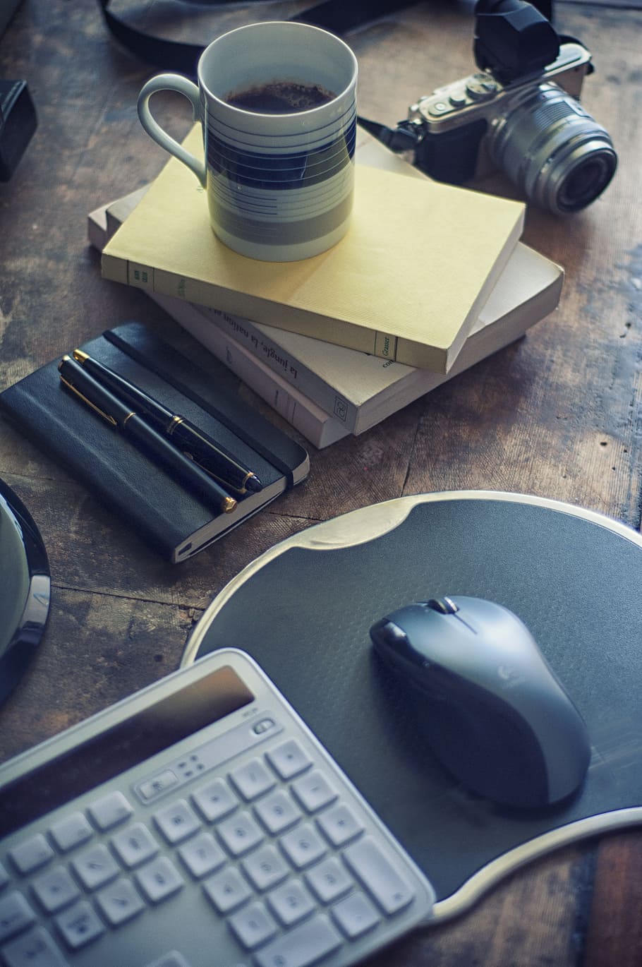 Computer Tastatur, Maus, Mauspad, Becher, Bücher, Kamera, braun, hölzern, Tafel, Kaffee, Kaffeebecher, Stift, Notizbuch, Büro, Arbeit, Innenministerium, Organisation, Tastatur, Computer, Blog, schreiben, Geschäft, Tabelle, Technologie, drinnen, High Angle View, Stillleben, Tasse, Essen und Trinken, Kaffeetasse, Taschenrechner, keine Leute, Getränk, Nahansicht, Möbel, Verbindung, Kommunikation, Veröffentlichung, Buch, 4K