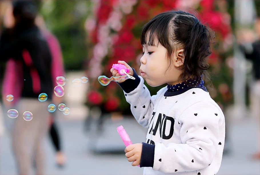 nena petita, portar, blanc, negre, suèter, celebració, ampolla de plàstic, bombolles, durant el dia, adorable, bufat, fons borrós, nen, bonic, cara, moda, noia, joia, poc, a l'aire lliure, parc, gent, jove, infància, descendència, centrar-se en primer pla, noies, bombolla, dones, persones incidentals, dia, innocència, femelles, fragilitat, naturalesa, vulnerabilitat, jugant, cintura cap amunt, 2K