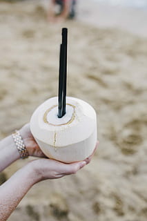 holding, fresh, coconut, Female, summer, fruit, holidays, vacations, fresh coconut, coconut water, juice, straw, coconut milk, beach, sand, human Hand, sea, outdoors, human body part, focus on foreground, hand, one person, real people, land, leisure activity, lifestyles, close-up, day, unrecognizable person, sweet, sweet food, personal perspective, women, finger, temptation, 4K