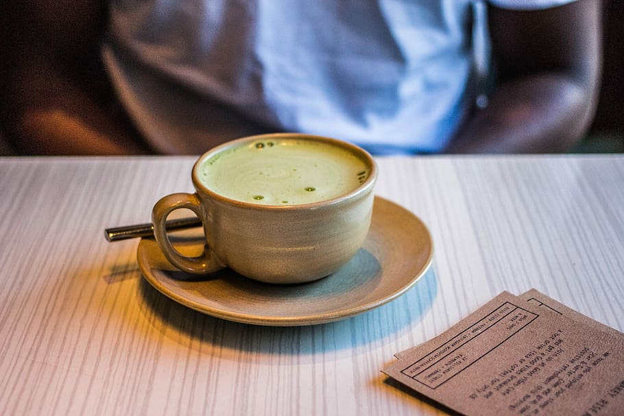 marró, ceràmica, tassa, plat, persona, assegut, frontal, tassa de cafè, ple, verd, líquid, taula, matcha, cafeteria, esmorzar, matcha latte, begudes, restaurant, te verd, te, beure, tassa i plat, menjar i beguda, una persona, adult, refresc, cafè, part del cos humà, beguda calenta, cafè - beguda, publicació, primer pla, llibre, a l'interior, mà, tassa de te, vaixella, 5K