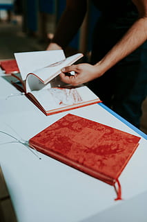 red, book, white, table, Red book, reading, literature, cookbook, people, working, men, human Hand, document, occupation, adults only, one person, adult, one woman only, only women, hand, real people, holding, midsection, publication, indoors, leisure activity, selective focus, lifestyles, human body part, close-up, paper, focus on foreground, unrecognizable person, finger, 5K