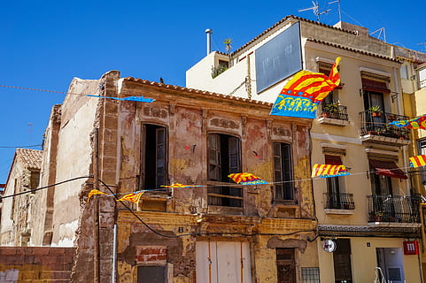 Fahnen in Valencia., Beige, Beton, Haus, Blau, Himmel, Gebäude, Flaggen, blauer Himmel, Fenster, Tür, die Architektur, Gebäudehülle, gebaute Struktur, Natur, Flachwinkelansicht, Stadt, keine Leute, Flagge, Tag, klarer Himmel, draußen, Geschichte, Balkon, die Vergangenheit, Sonnenlicht, Reiseziele, architektonische Säule, 5K, CC0, gemeinfrei, lizenzfrei