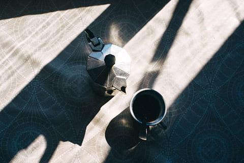 gray, stainless, steel cup, beside, moka pot, top, table, coffee, tea, cup, teapot, hot, drink, shadow, food and drink, refreshment, sunlight, high angle view, coffee - drink, coffee cup, mug, indoors, human body part, one person, holding, day, human hand, close-up, hand, 5K, CC0, public domain, royalty free