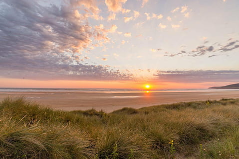 photo, green, grass, filed, ocean, golden, hour, sunset, beach, dunes, travel, sea, landscape, vacation, sand, coast, sunrise, scenic, orange, sun, coastline, light, horizon, outdoor, seaside, environment, tourism, nature, sky, water, shore, clouds, scenics - nature, beauty in nature, cloud - sky, tranquil scene, tranquility, plant, land, horizon over water, no people, marram grass, lens flare, outdoors, 1080P, CC0, public domain, royalty free
