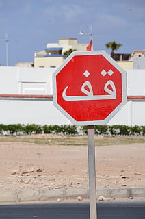 Schild, Arabisch, halt, Kommunikation, rot, Zeichen, Warnschild, Tag, die Architektur, Straße, Natur, Fokus auf den Vordergrund, Stadt, keine Leute, Straßenschild, draußen, Gebäudehülle, Text, gebaute Struktur, Pole, Gebäude, Beratung, Nahansicht, Warnsymbol, 2K, CC0, gemeinfrei, lizenzfrei