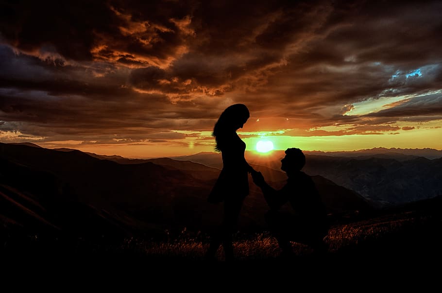 home, proposant, dona, posta de sol, vespre, tarda, alba, retroil·luminat, silueta, panoràmica, a l'aire lliure, gent, escènic, proposta, matrimoni, amor, romanç, família, junts, cel, núvol - cel, dues persones, bellesa a la natura, unió, muntanya, escenics - natura, de peu, naturalesa, activitat d'oci, persones reals, adult, dones, tranquil·litat, color taronja, emoció positiva, parella - relació, fill, 4K