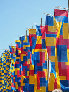 flags, blow, flutter, commemorative event, blue, red, yellow, multi colored, clear sky, sky, low angle view, no people, day, nature, hanging, architecture, sunlight, outdoors, flag, pattern, decoration, side by side, built structure, textile, security, 4K, CC0, public domain, royalty free