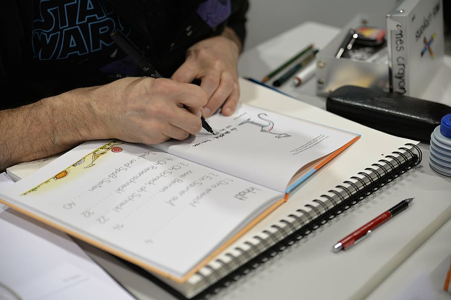 Künstler, Zeichnung, Comic, Comic Con, drinnen, eine Person, menschliche Hand, Stift, Papier-, Männer, Hand, Mittelteil, Tabelle, Schreiben, halten, menschliches Körperteil, Nahansicht, Veröffentlichung, Besetzung, Bleistift, Buch, High Angle View, Bildung, Notizblock, 5K