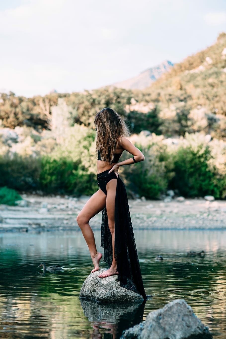 donna, indossare, nero, raccolto, superiore, in piedi, grigio, pietra, corpo, acqua, giorno, crop top, corpo d'acqua, donne, lago, natura, all'aperto, una persona, estate, persone, femmine, etnia caucasica, fiume, giovane adulto, bellissimo, rilassamento, bellezza, adulto, bellezza nella natura, stili di vita, scena tranquilla, riflessione, capelli lunghi, persone reali, acconciatura, capelli, attività di svago, concentrarsi sulle conoscenze acquisite, lungomare, retrovisore, guardando a vista, 5K