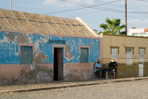 hombre, mujer, sentado, fuera de, casa, junto a, la carretera, dos, persona, marrón, hormigón, edificio, tiempo de día, arquitectura, árbol, palmera, estructura construida, exterior del edificio, día, gente real, naturaleza, texto, cielo, gente, hombres, ciudad, luz del sol, al aire libre, estilos de vida, escritura occidental, en pie, actividad de ocio, adulto, 4K, CC0, dominio público, libre de derechos