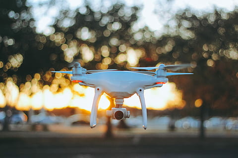 hvid quadcopter drone, hvid, sort, video, streaming, drone, bokeh lys, dj iphantom4, dji phantom, fantom, fantom 4, luftfartøj, transportmidler, transportform, fly, ingen mennesker, himmel, natur, flyvende, selektiv fokusering, bevægelse, lufthavn bane, udendørs, solnedgang, fokus på forgrunden, belyst, Midt i luften, lufthavn, rejse, træ, luftfartsindustrien, 4K, CC0, offentligt domæne, royaltyfrie